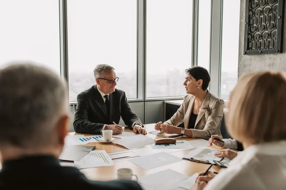 Two senior colleagues talking across a meeting table