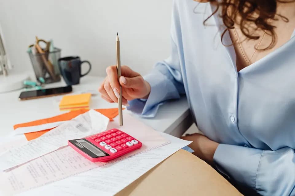 A colleague totalling figures at a desk covered in paperwork