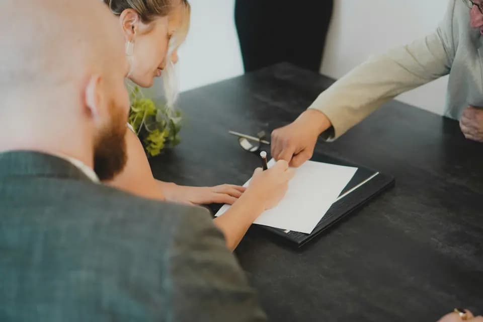 Two people signing a document together at a desk
