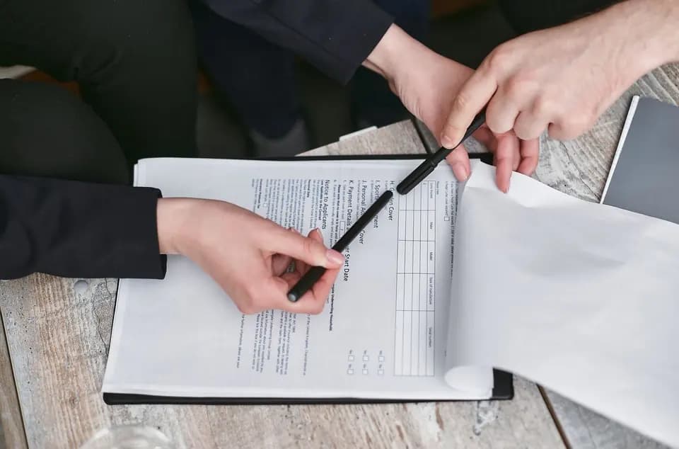 Hands reviewing a printed document with a pen
