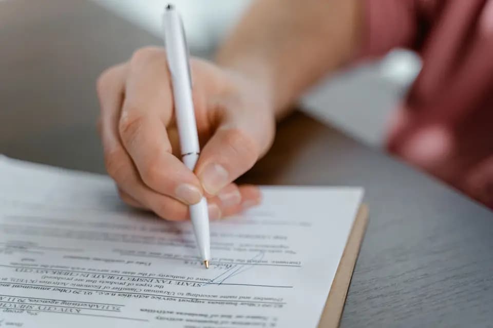 A signature being written on a printed agreement