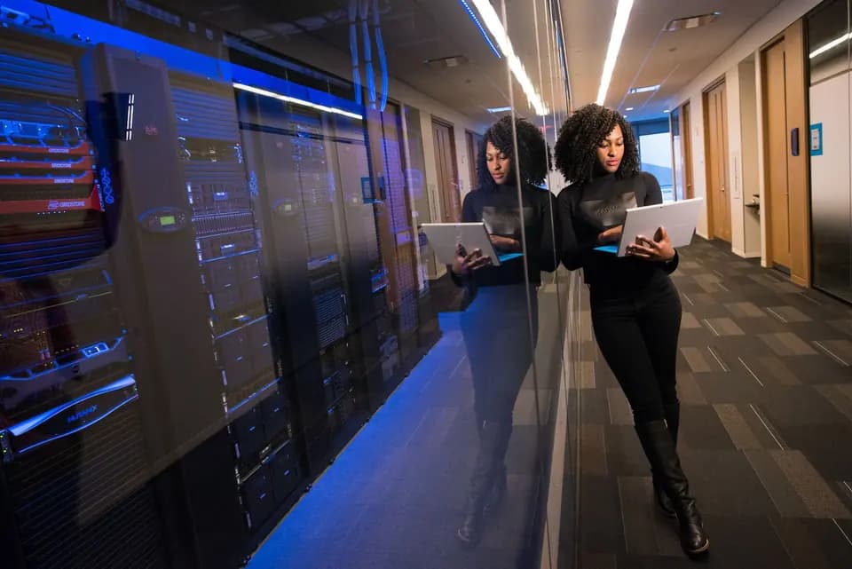 An engineer walking a data-centre aisle between server cabinets