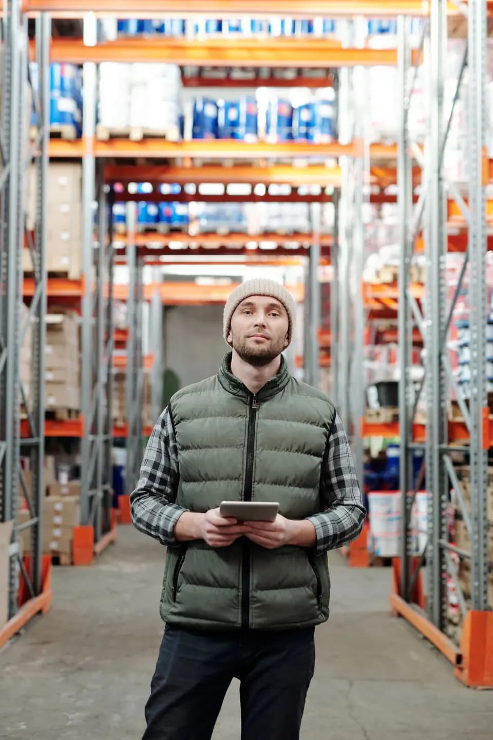 A worker reviewing records on a tablet in a warehouse aisle