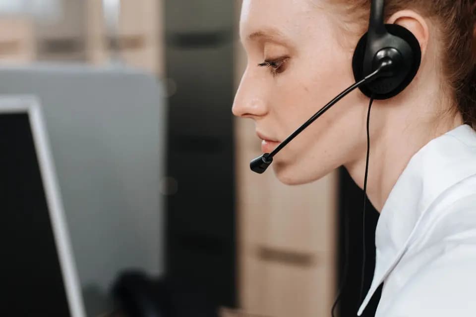 A support agent in a headset seen from the side at a desk