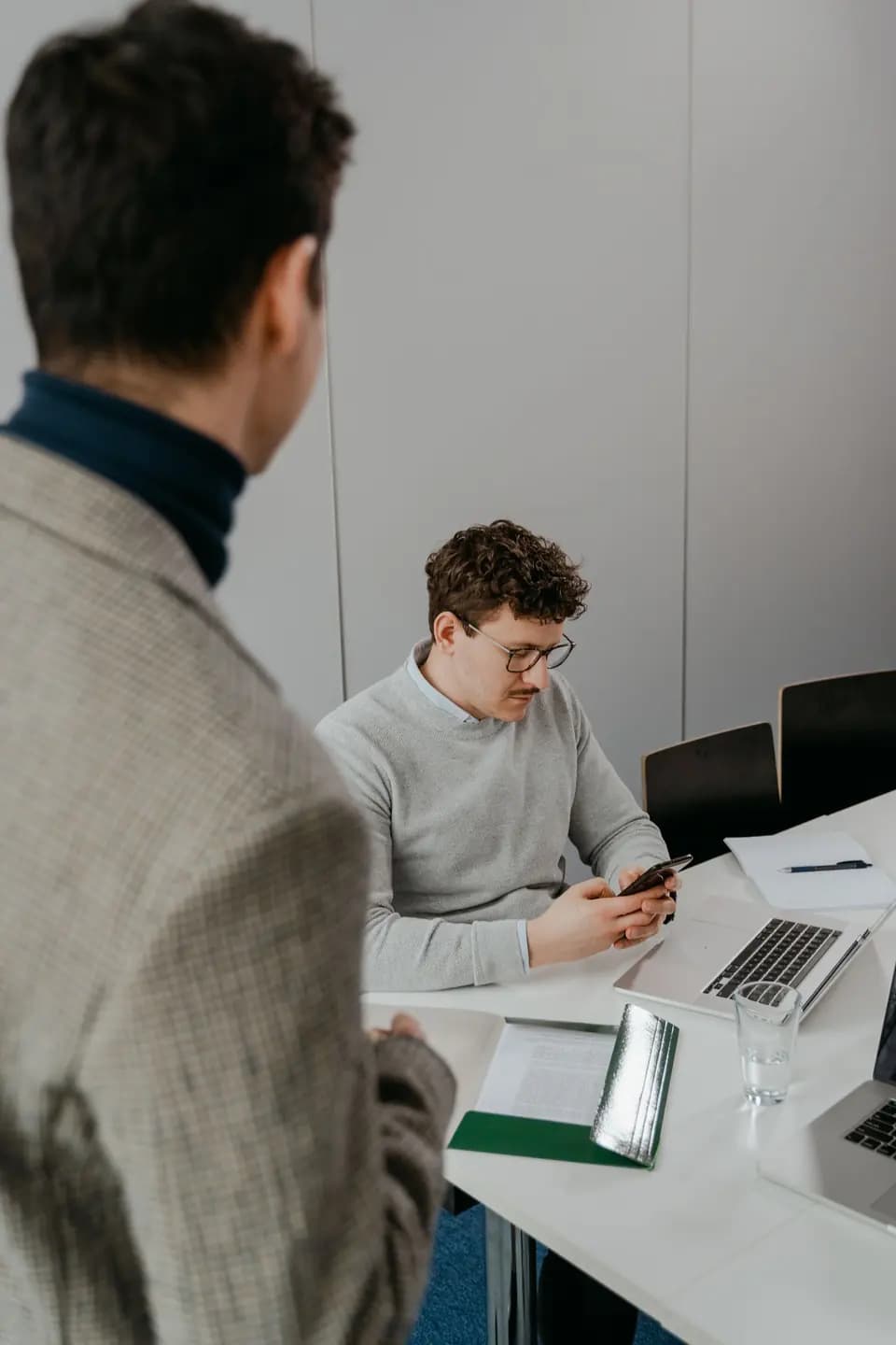Two colleagues working across laptops at a shared desk
