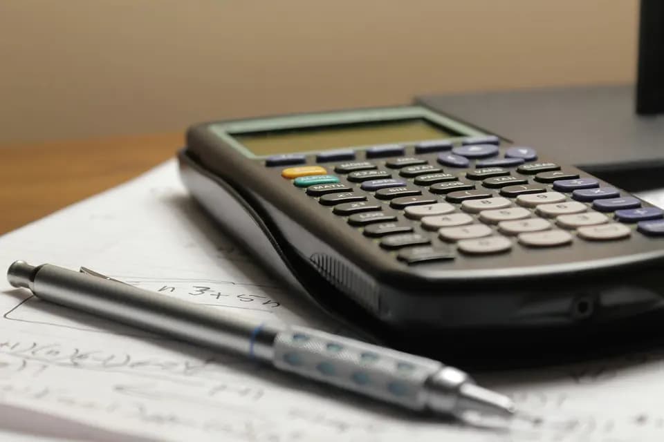 A calculator and pen resting on a printed statement