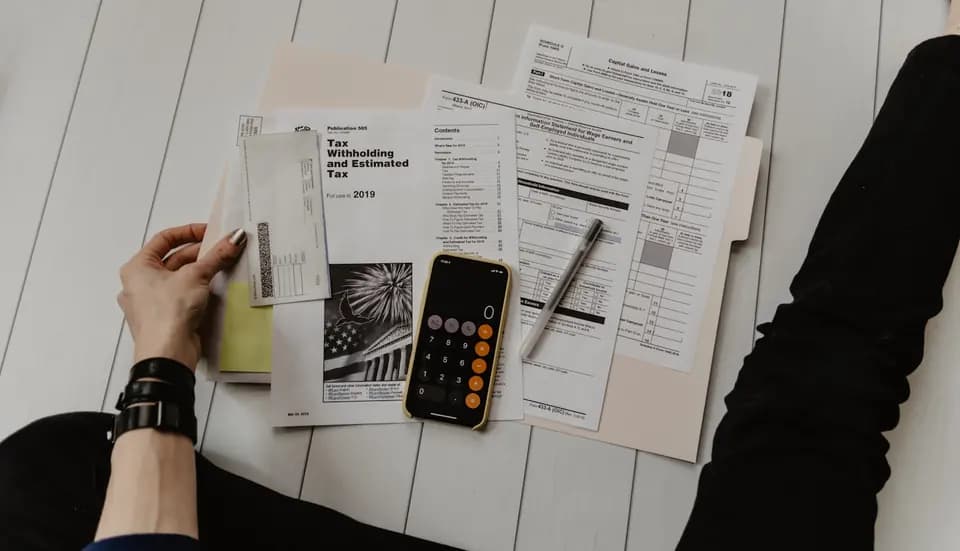 Paperwork held beside a calculator and pen