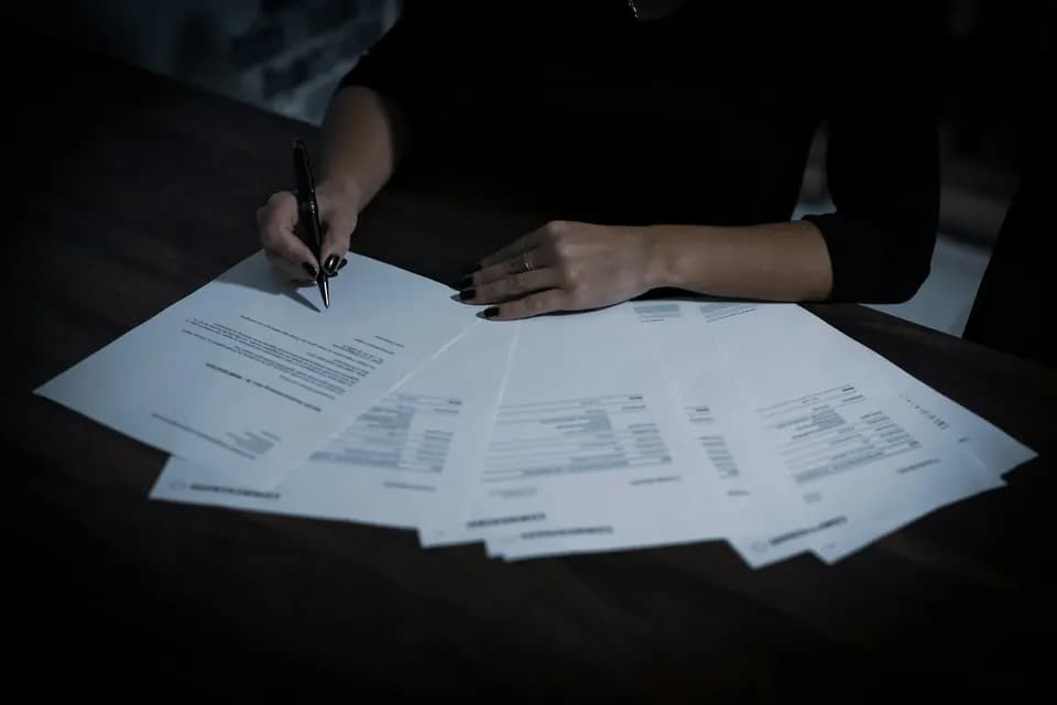 Someone working at a table covered in paperwork